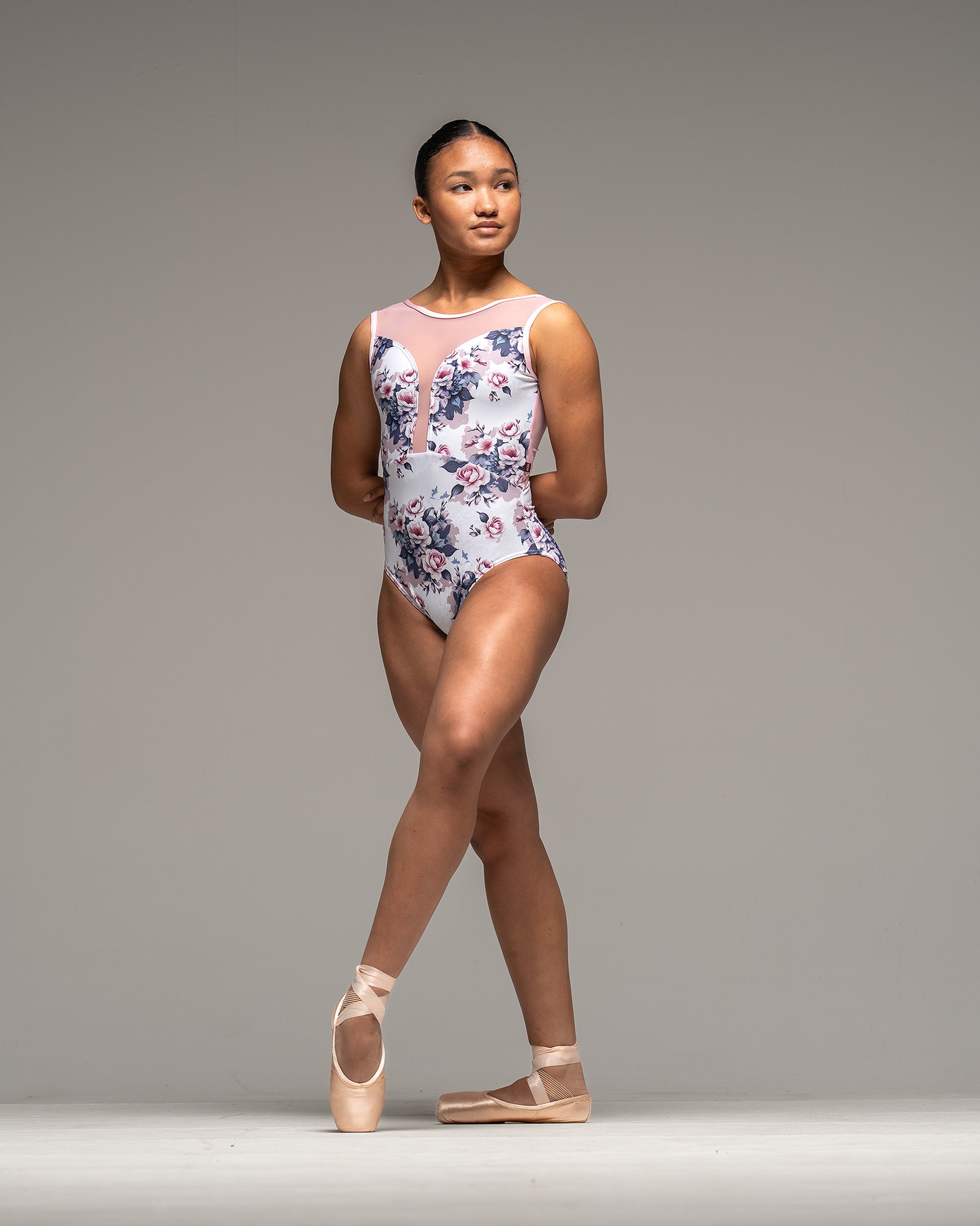 Dancer wearing ballet leotard in white, pink and blue floral print with pink mesh