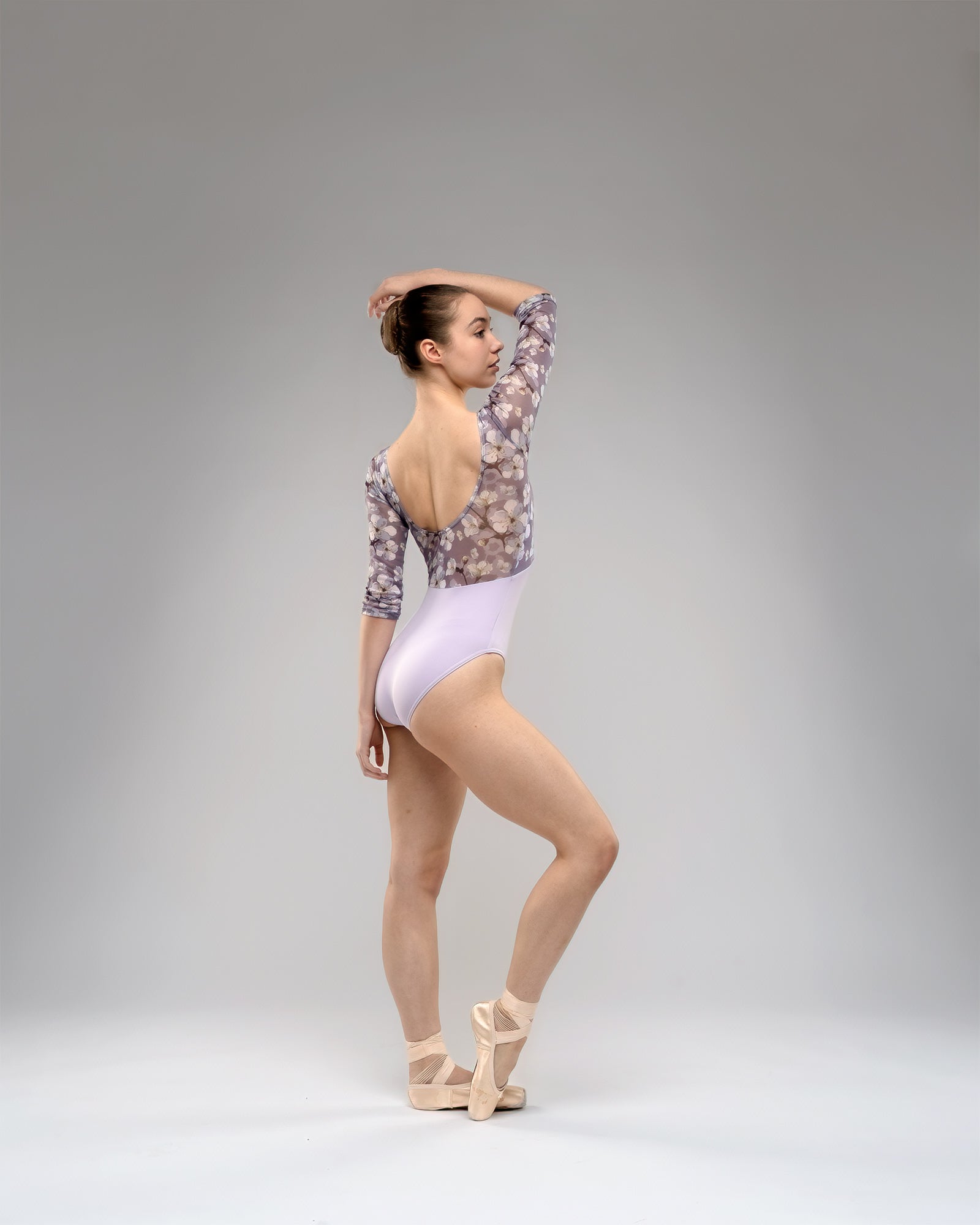 Ballet dancer wearing lilac leotard With long sleeves, floral print mash upper body lilac white and purple