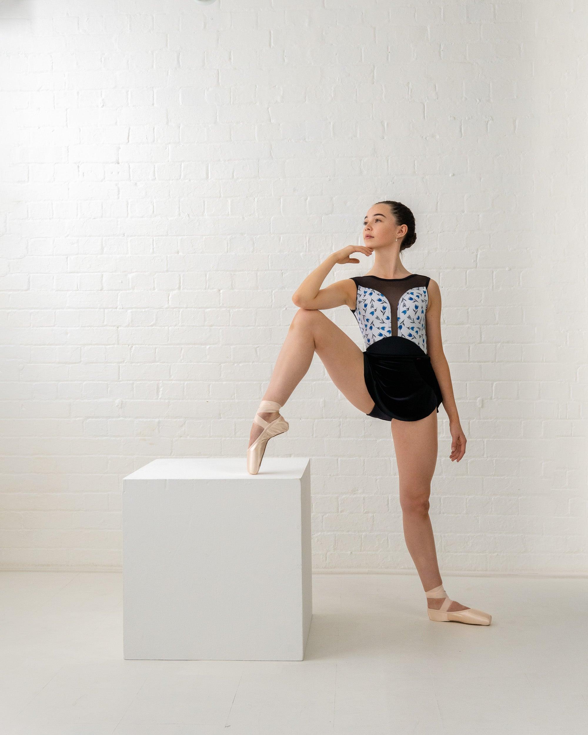 Dancer wearing  tulip print sleeveless  leotard  with black matte bottom and mesh ruched back and matching black SAB skirt